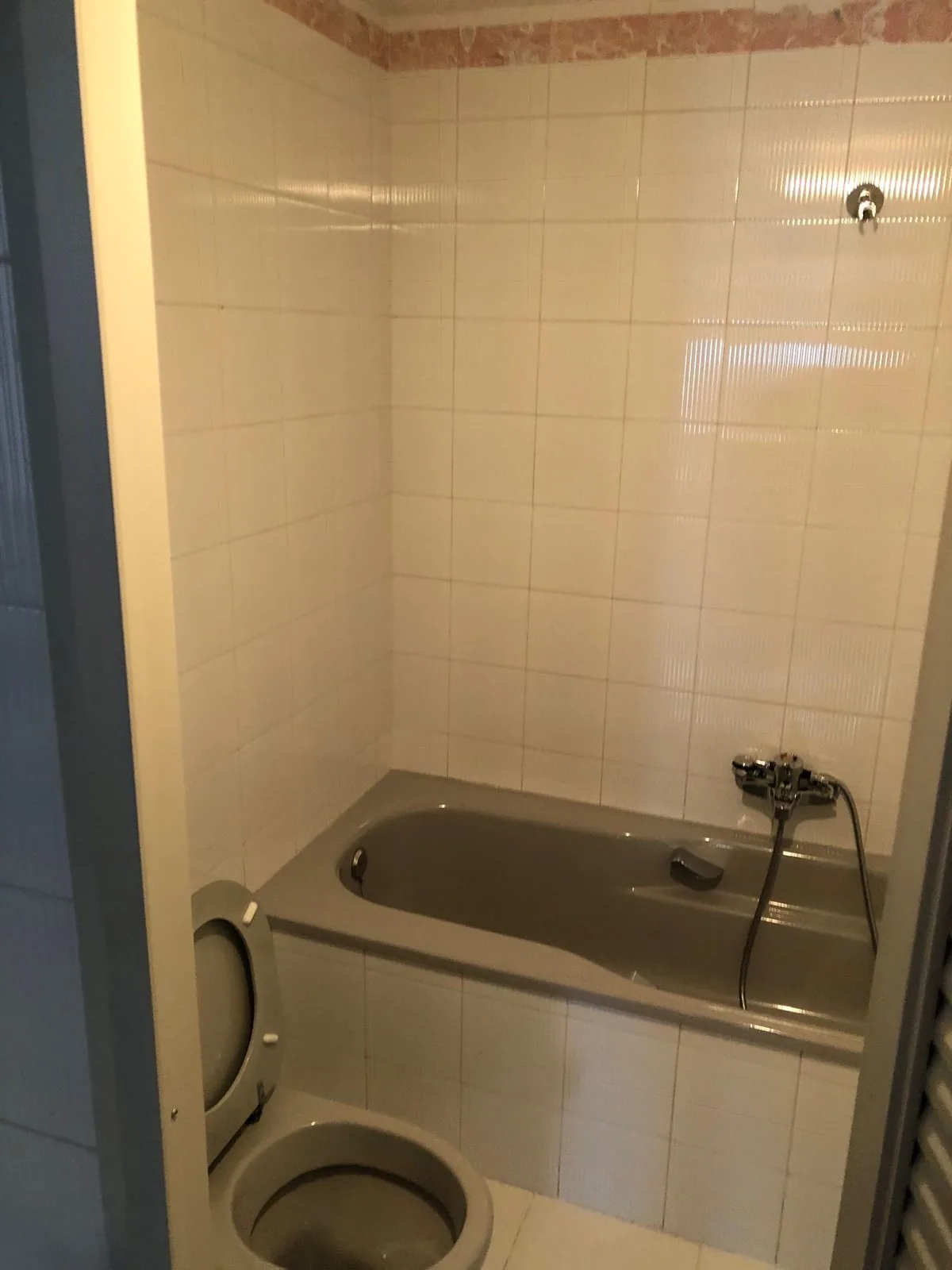 El baño antes de la obra, con la bañera y el alicatado claro