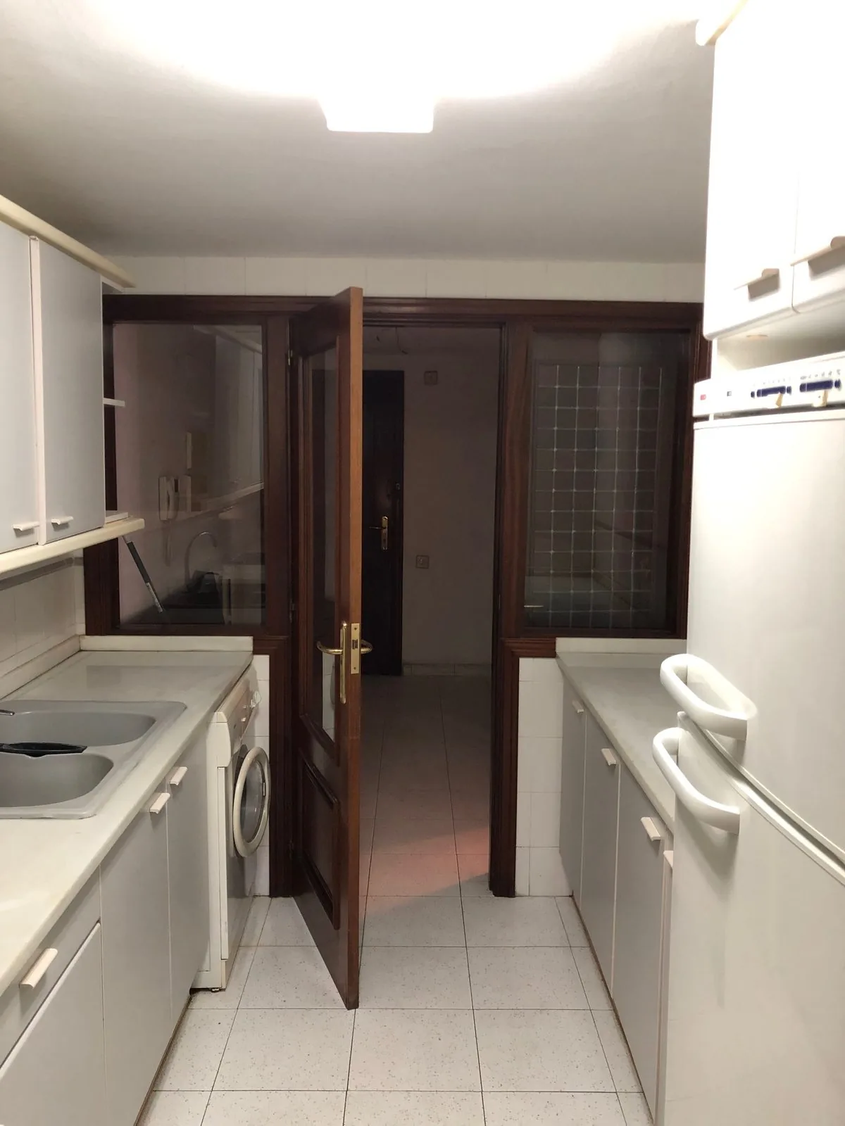 La cocina antes de la obra, cerrada, con los muebles blancos y la puerta de madera