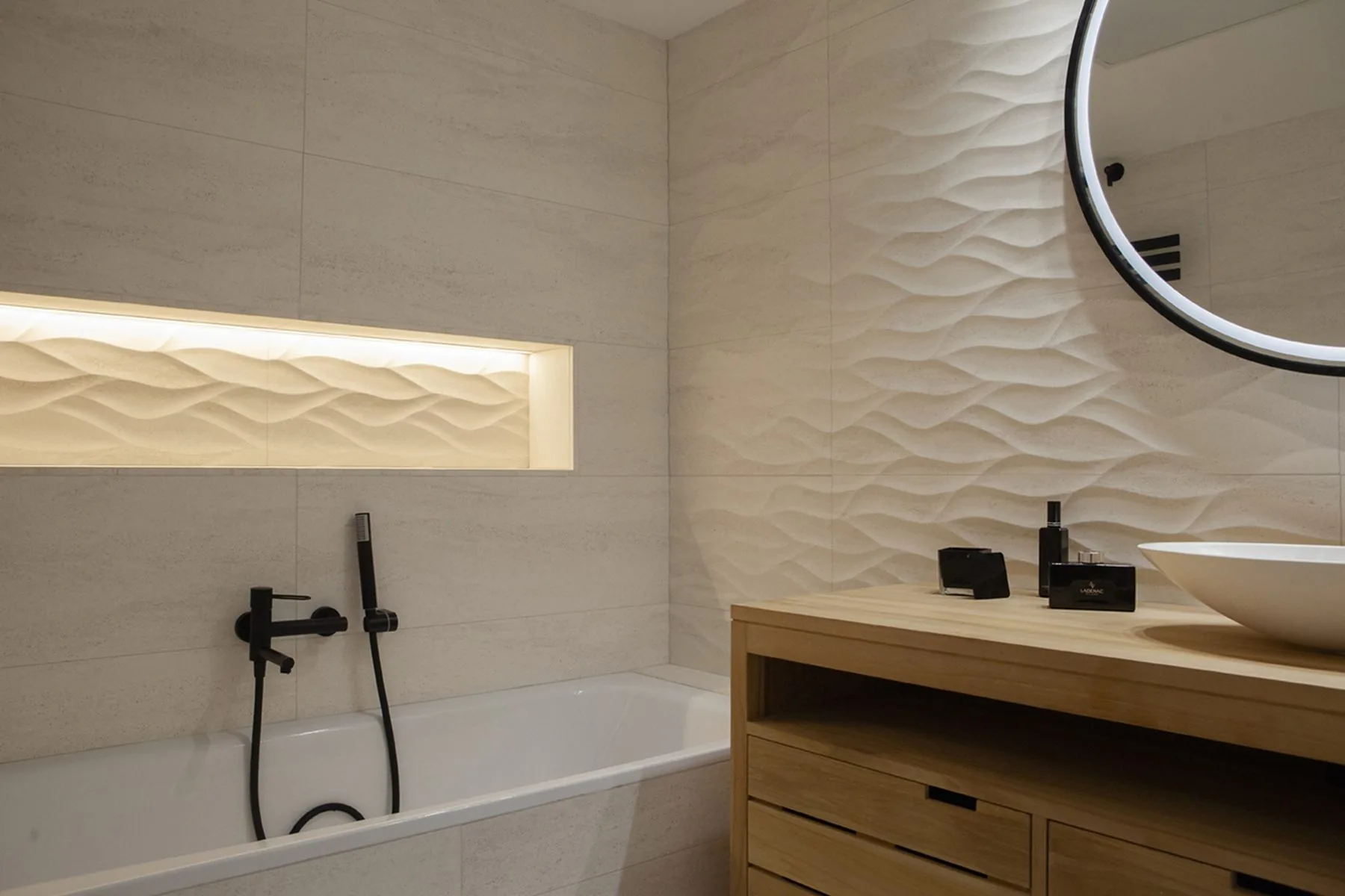 La bañera bajo la hornacina iluminada, sobre el revestimiento de relieve ondulado