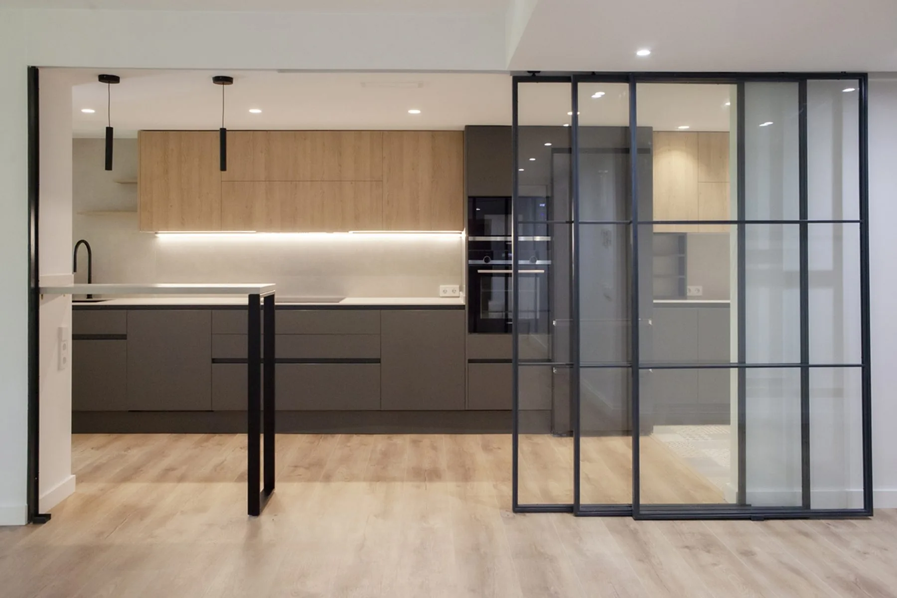 La cocina vista desde el salón-comedor a través de la cristalera de acero — obra AGM9