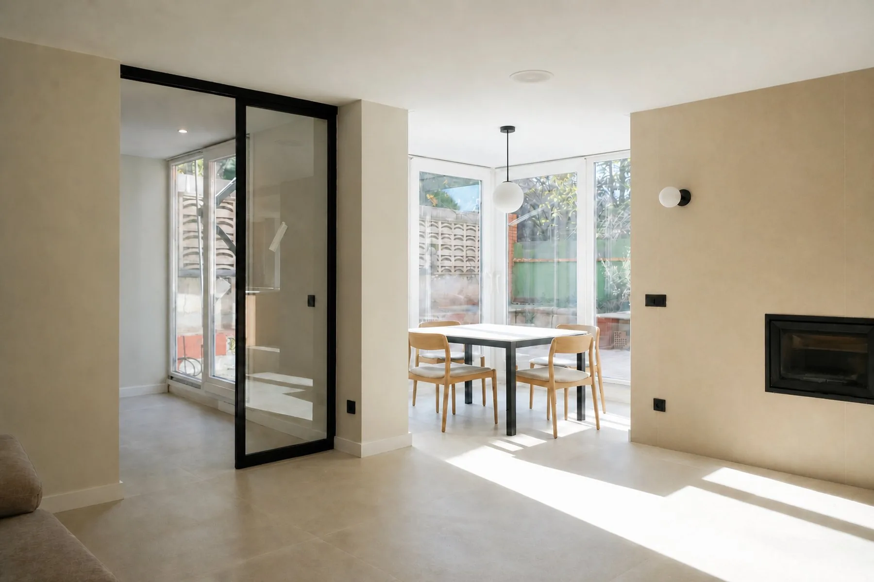 La galería, con las cristaleras hacia el jardín y la mesa del comedor