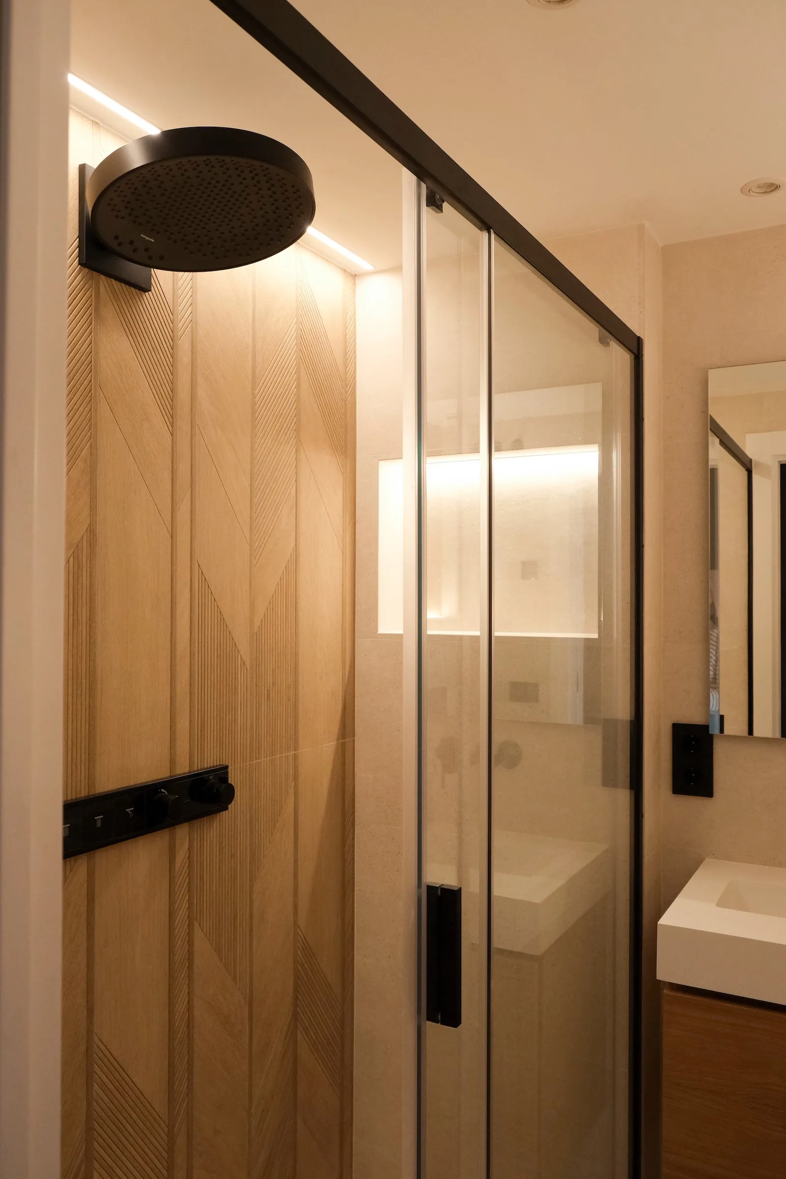 La ducha del tercer baño, revestida de madera en espiga con mampara negra