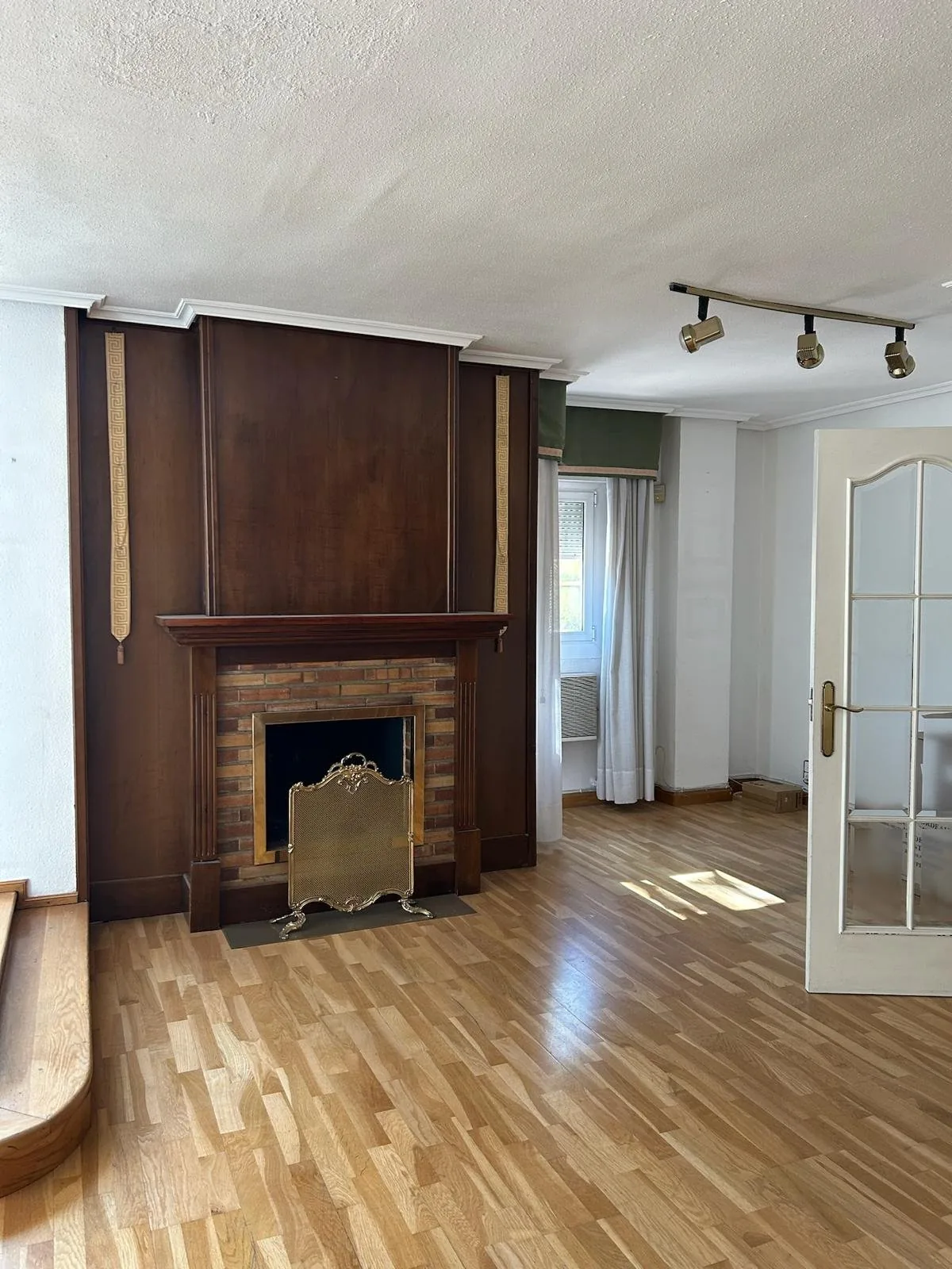 El salón antes de la obra, con la chimenea antigua de madera oscura