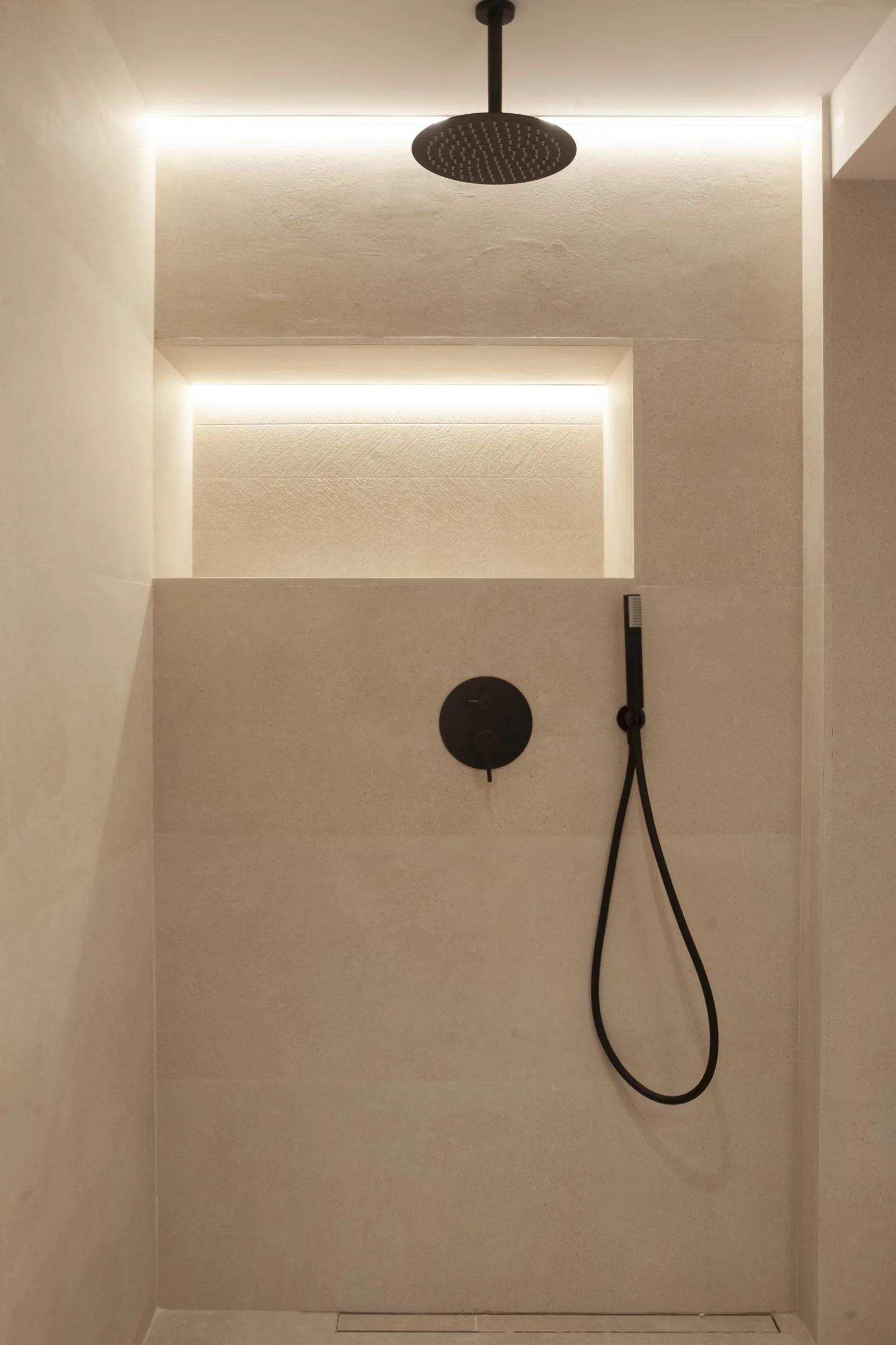 La ducha del baño, con la hornacina iluminada en piedra clara
