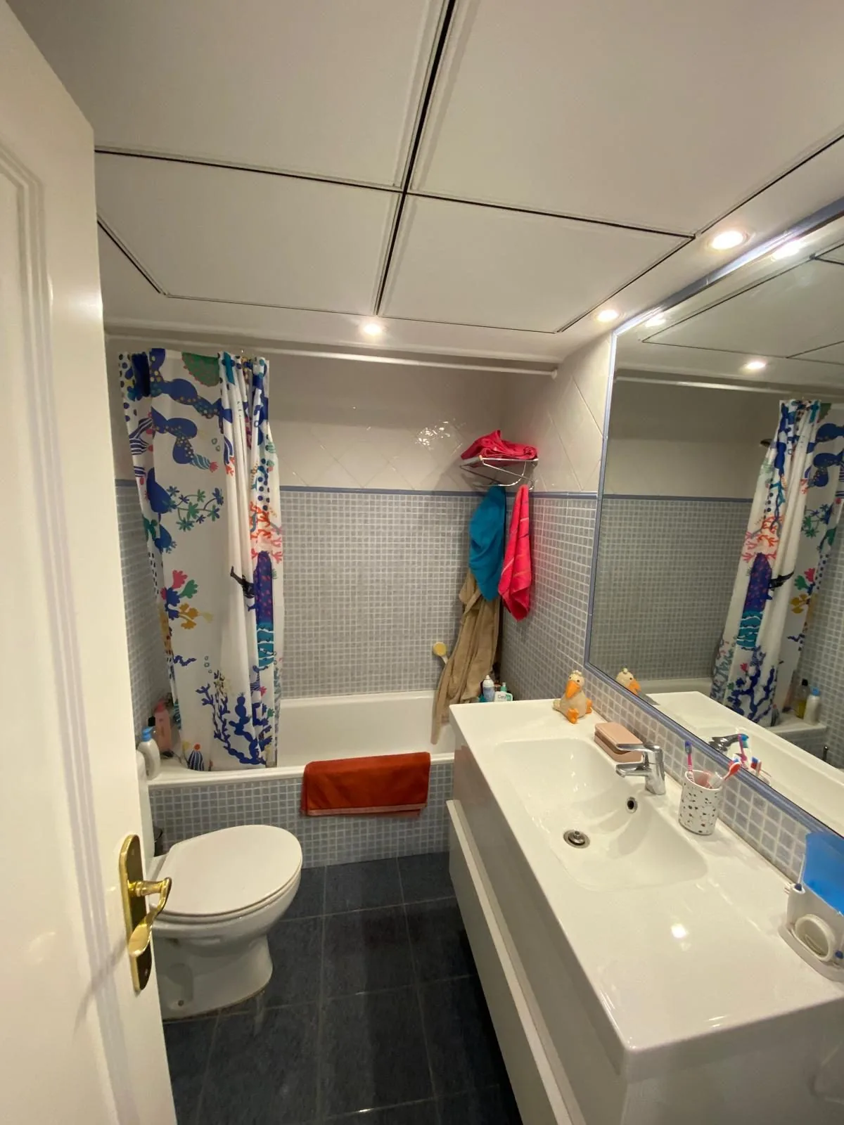 El baño antes de la obra, con la bañera, la encimera corrida y el alicatado con cenefa