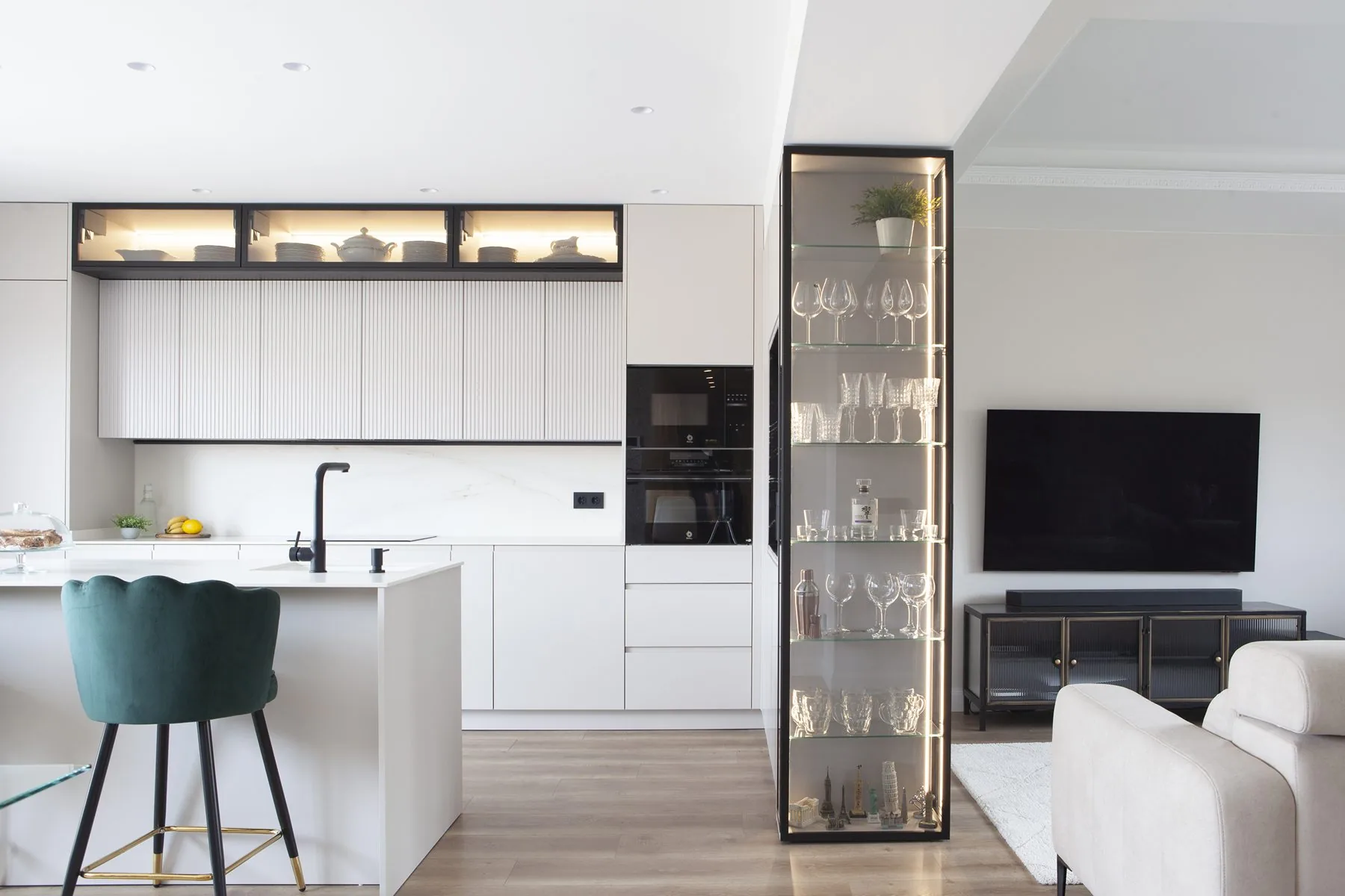 La cocina abierta al salón, con la vitrina de vidrio y perfilería negra — obra FU32