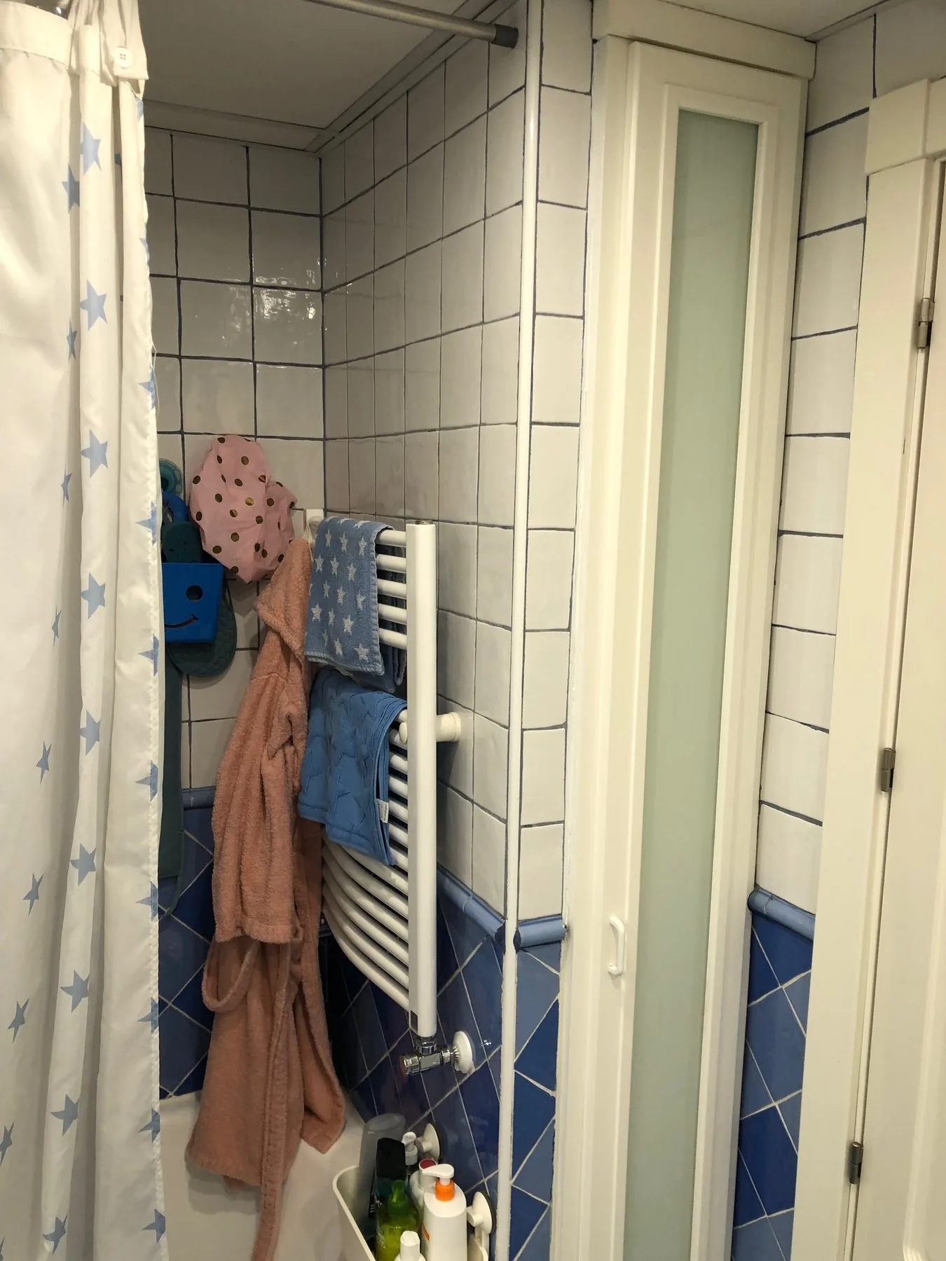 La bañera que había antes de la obra, tras la cortina, con el radiador toallero y el azulejo azul en rombos