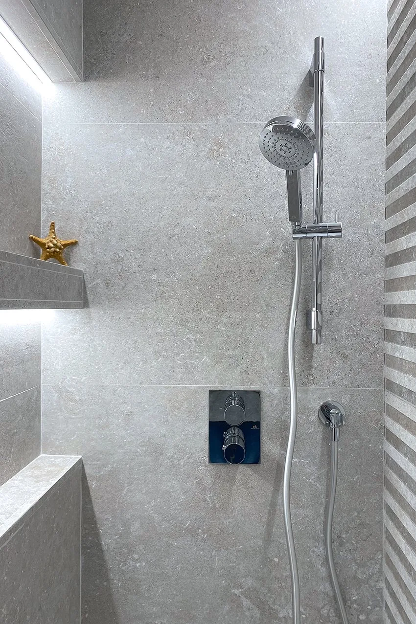 La ducha del baño general hoy, con las dos hornacinas iluminadas abiertas en la misma piedra gris