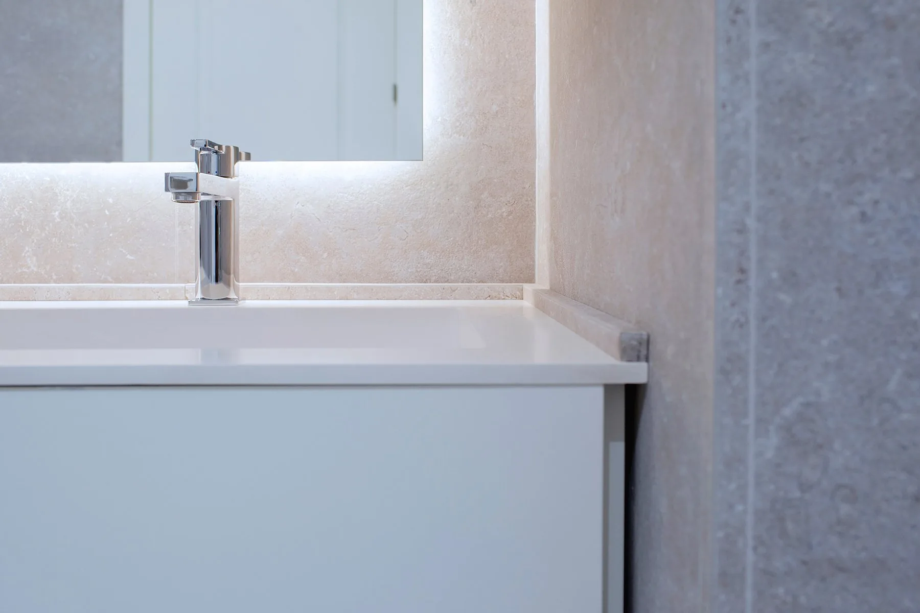 El paño del mueble del baño general hoy: el mueble blanco de cajones y el espejo retroiluminado sobre la piedra gris