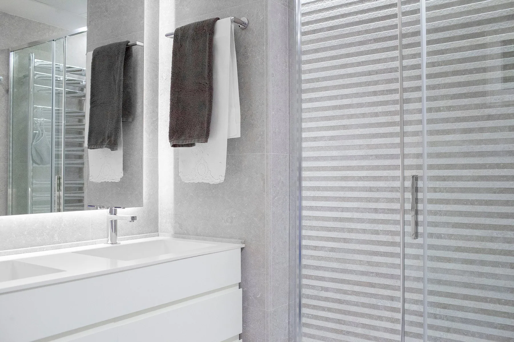 El baño general terminado: el mueble blanco de cajones y el espejo retroiluminado — obra JZ14