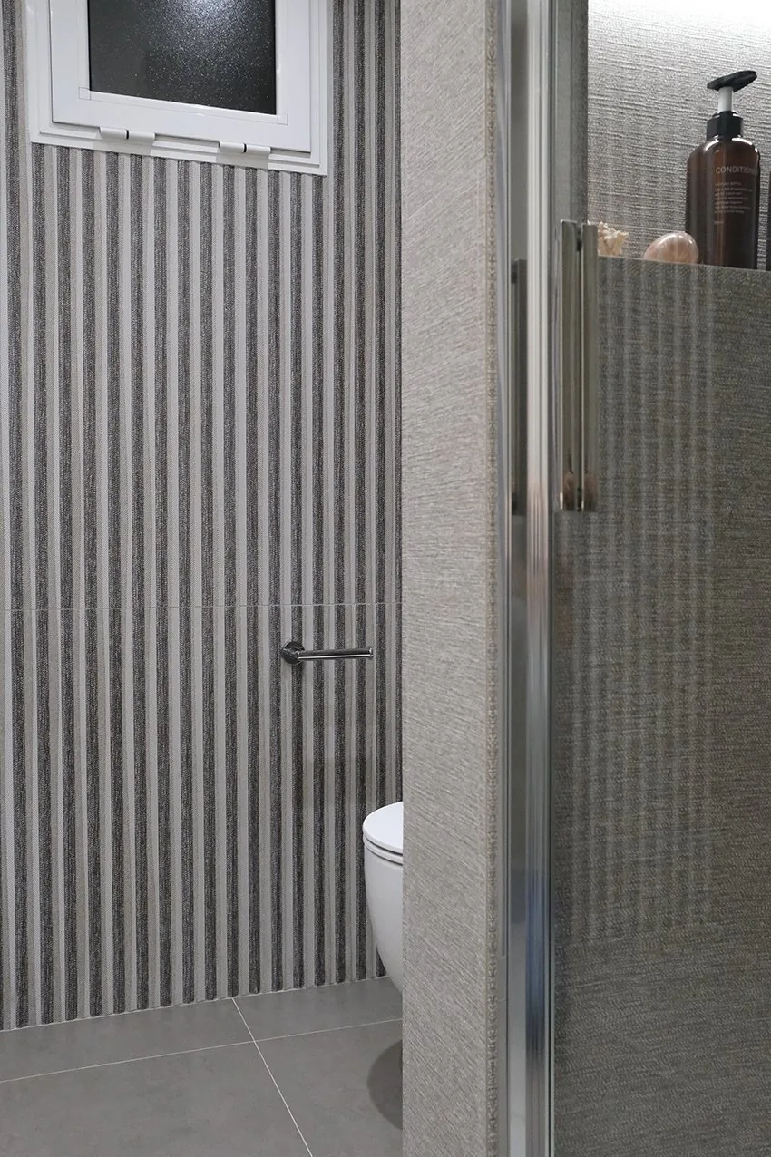 La pieza de relieve estriado vertical junto a la mampara de la ducha del baño suite