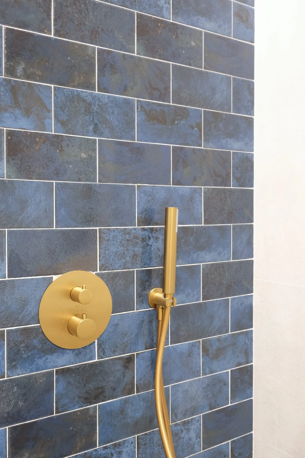 Detalle del azulejo azul de L'Antic Colonial y la grifería dorada de la ducha