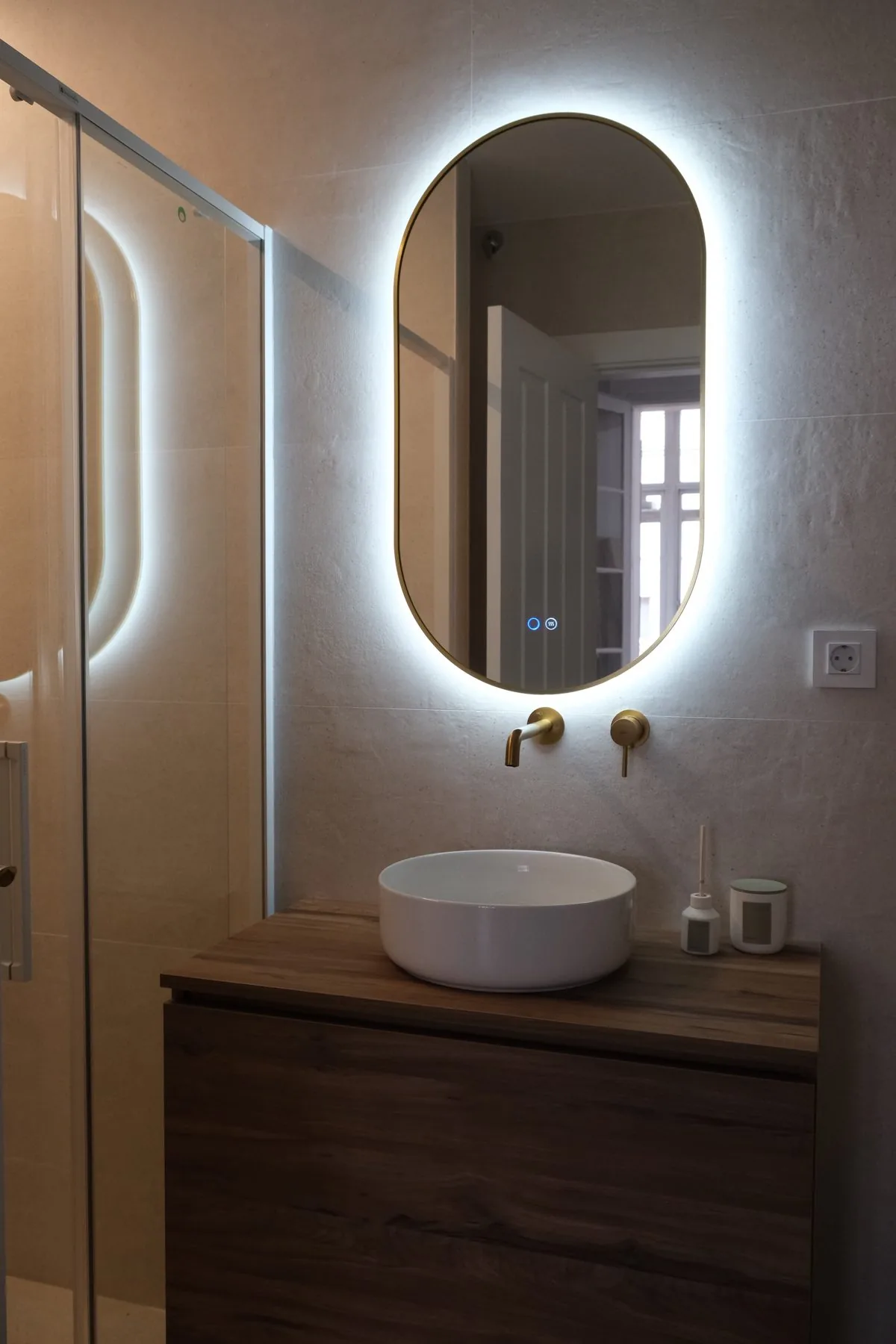 Baño de la suite: el lavabo redondo, el espejo retroiluminado y el azulejo azul de la ducha