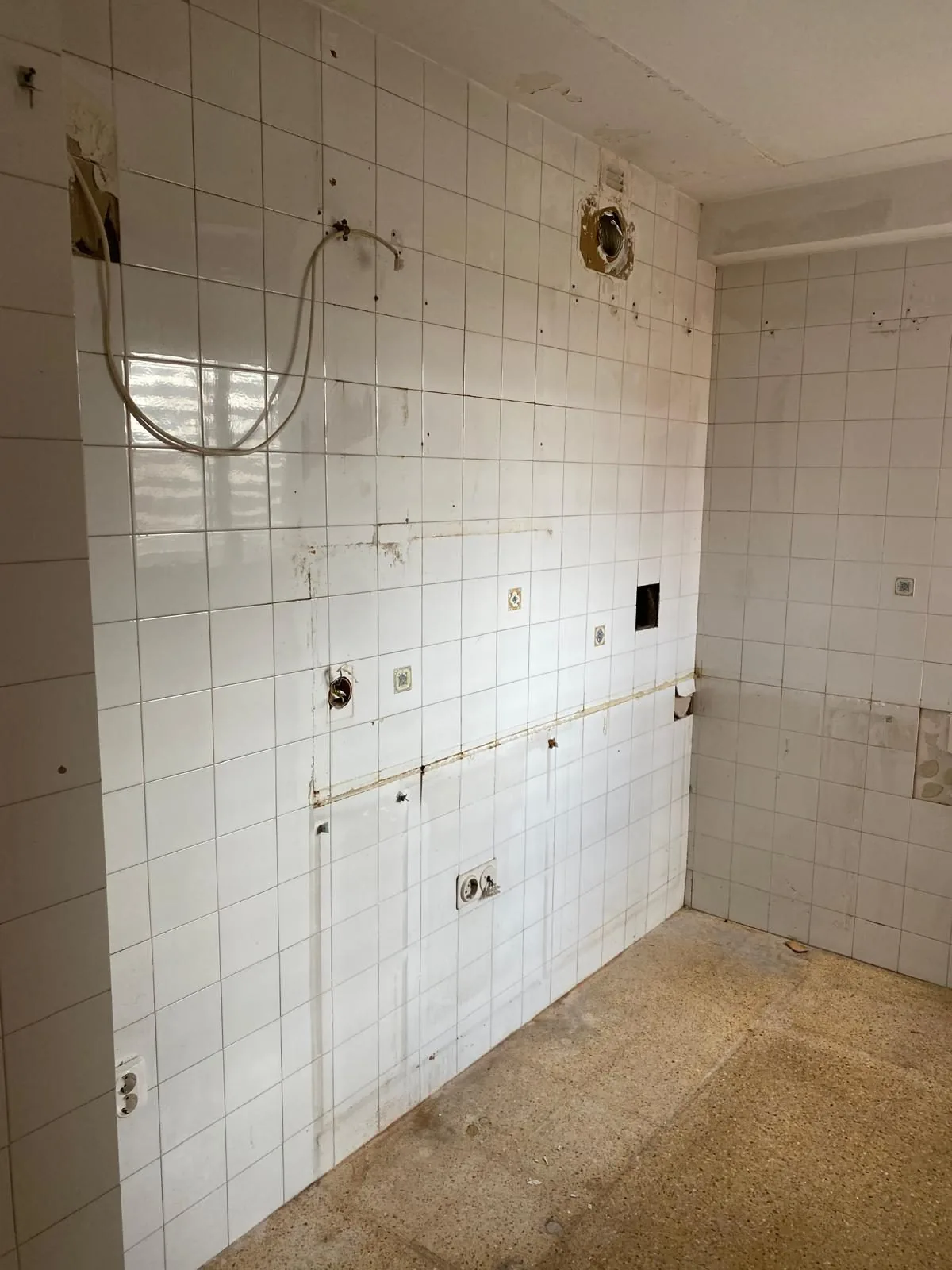 Una de las piezas húmedas durante la obra, con el alicatado picado y las instalaciones a la vista