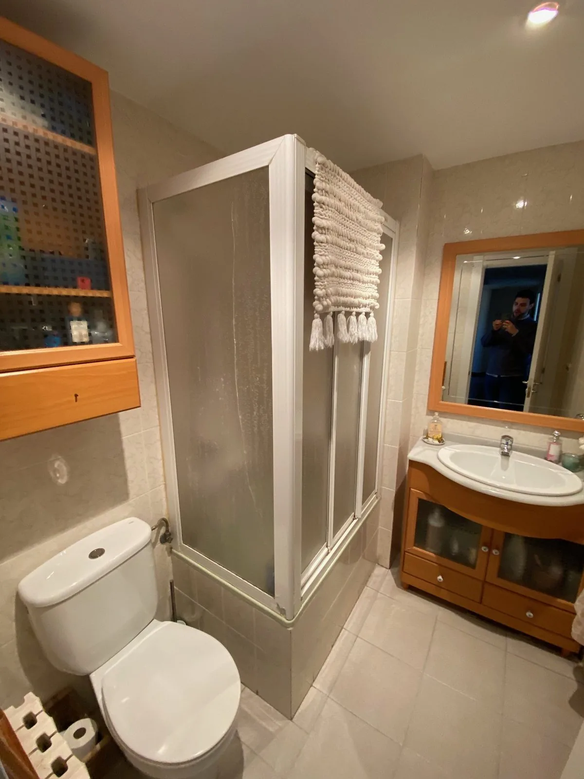 El baño antes de la obra, con el plato de ducha, la mampara de aluminio y el mueble de madera al fondo