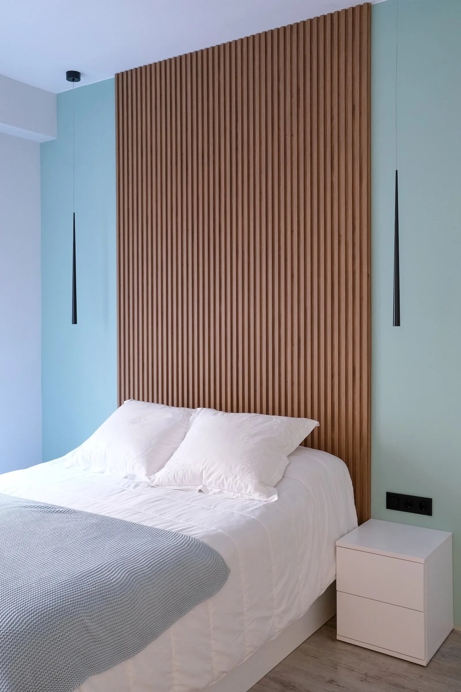 El dormitorio principal, con el cabecero de madera ranurada sobre la pared en verde agua